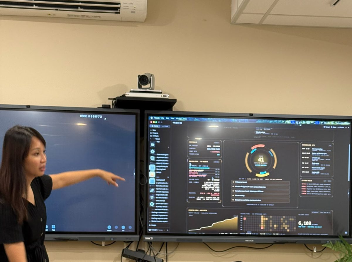 Photograph of Geargina Tan (Coach Gina), Singapore-based AI workshop facilitator and COO of WTFox.ai, demoing her own Claude dashboard at the Claude Masterclass 101 with Cogentic AI Partners, Singapore, August 2026. Real photo. Claude workshop in Singapore.